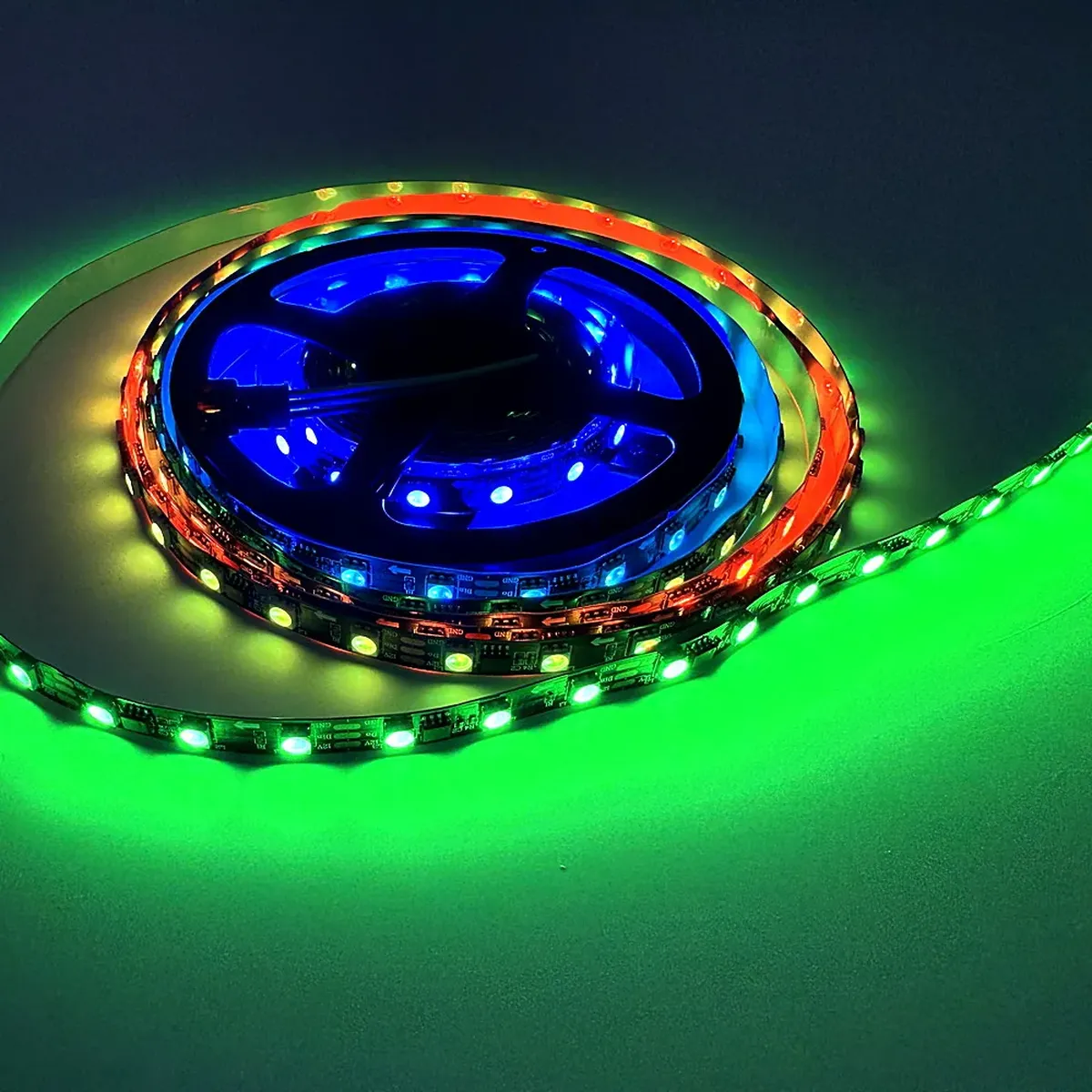 Close product photograph of addressable RGB LED strip with the driver ICs visible between the LED groups on a flexible black PCB
