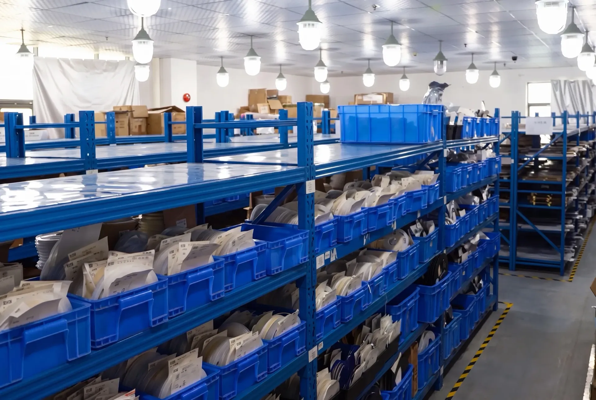 Rows of racking and blue parts bins where export orders are picked at the factory end of the supply chain