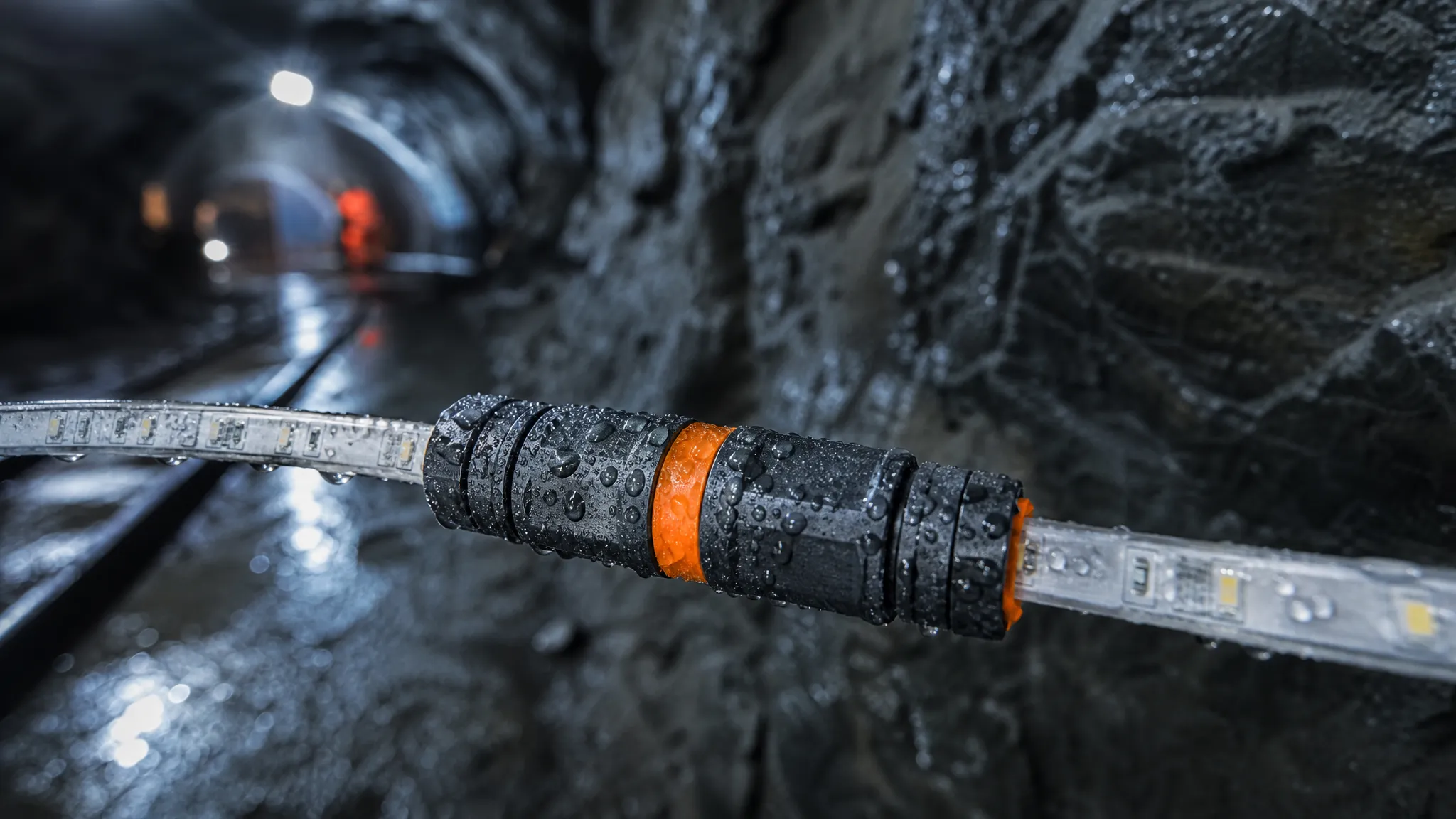 Rendered illustration (not project photography): a sealed IP68 connector joining two segments of a mine strip inside a wet tunnel