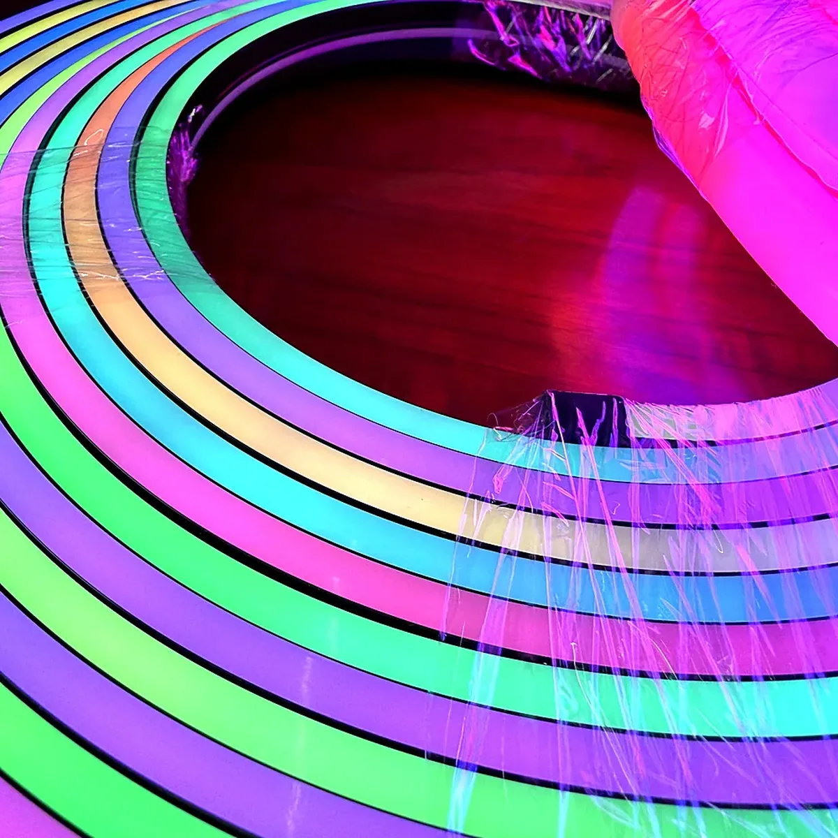 Close-up of several lit runs of flexible LED neon flex curving together, showing even colour along the diffuser face