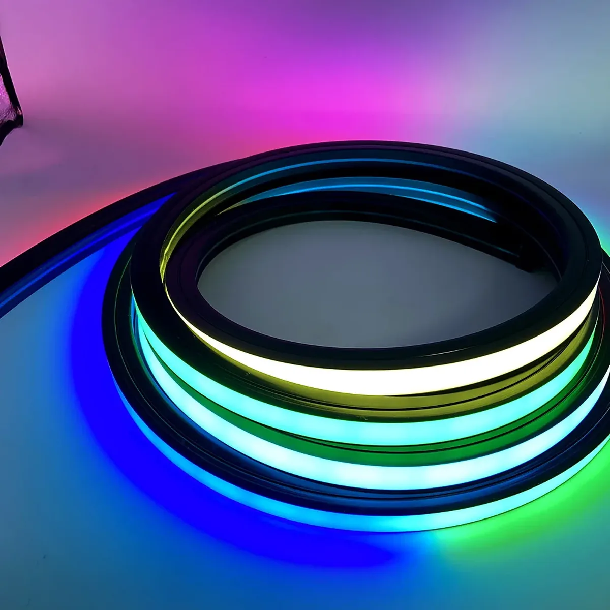 A coil of lit 20 mm RGB LED neon flex on a pale surface, with several colours visible along the diffuser face at once