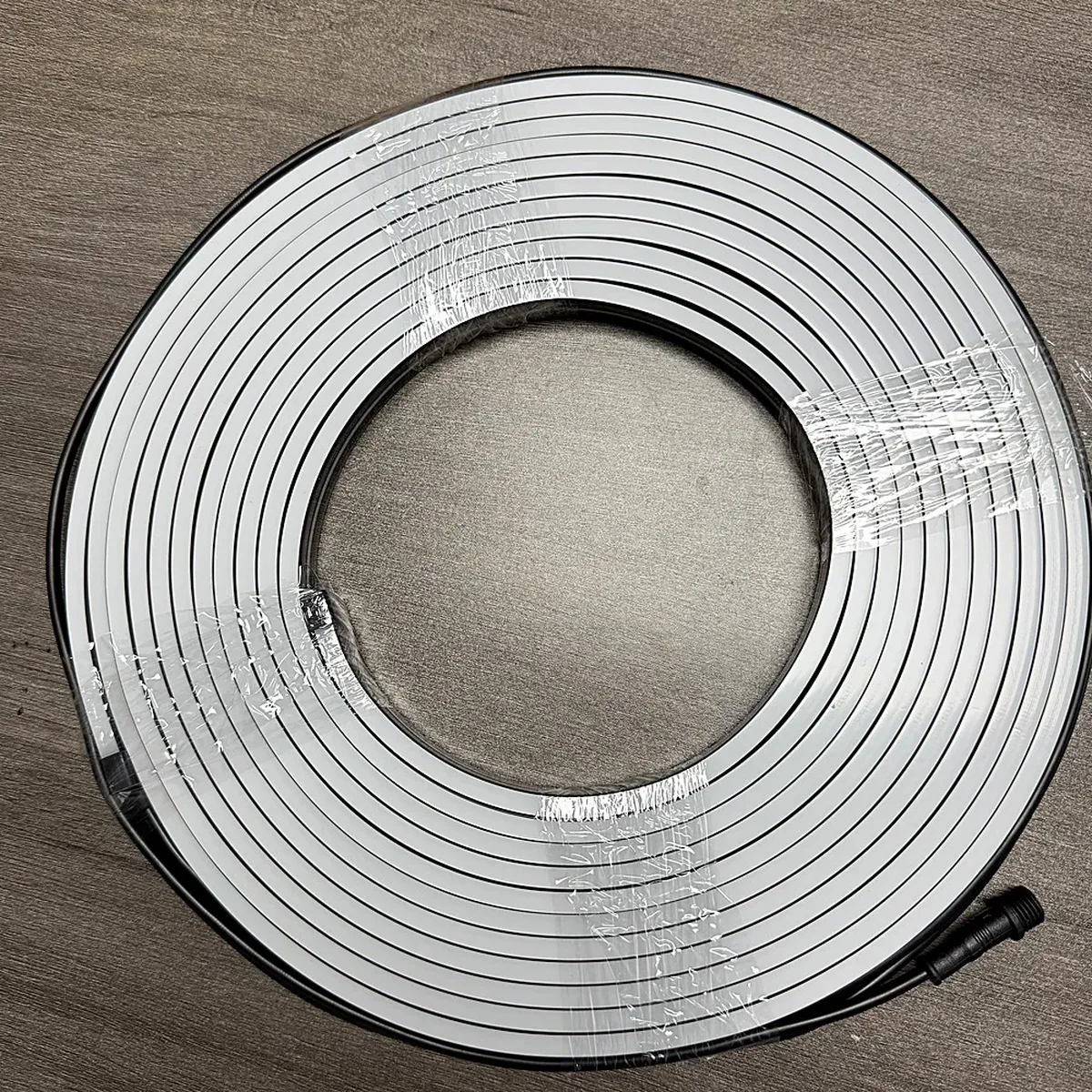 Unlit flexible LED neon flex coiled on a workbench, showing the extruded silicone profile and its translucent diffuser face
