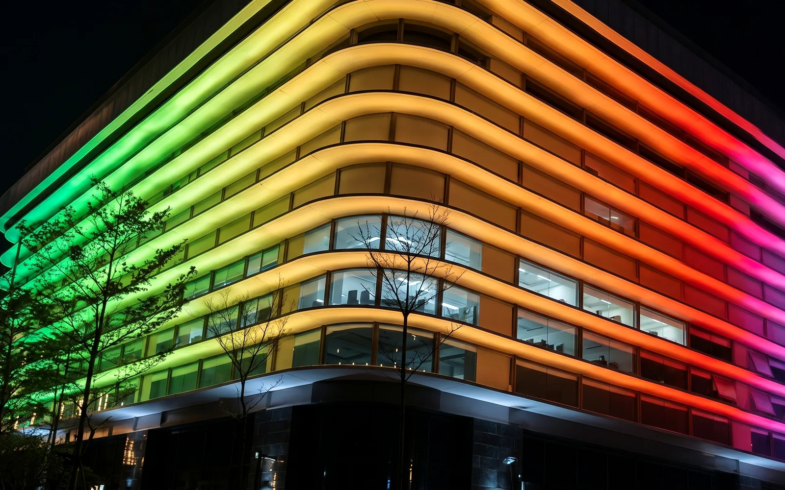 Wide view of the delivered German plaza facade glowing with a full-color DMX wall washer wash across its horizontal bands