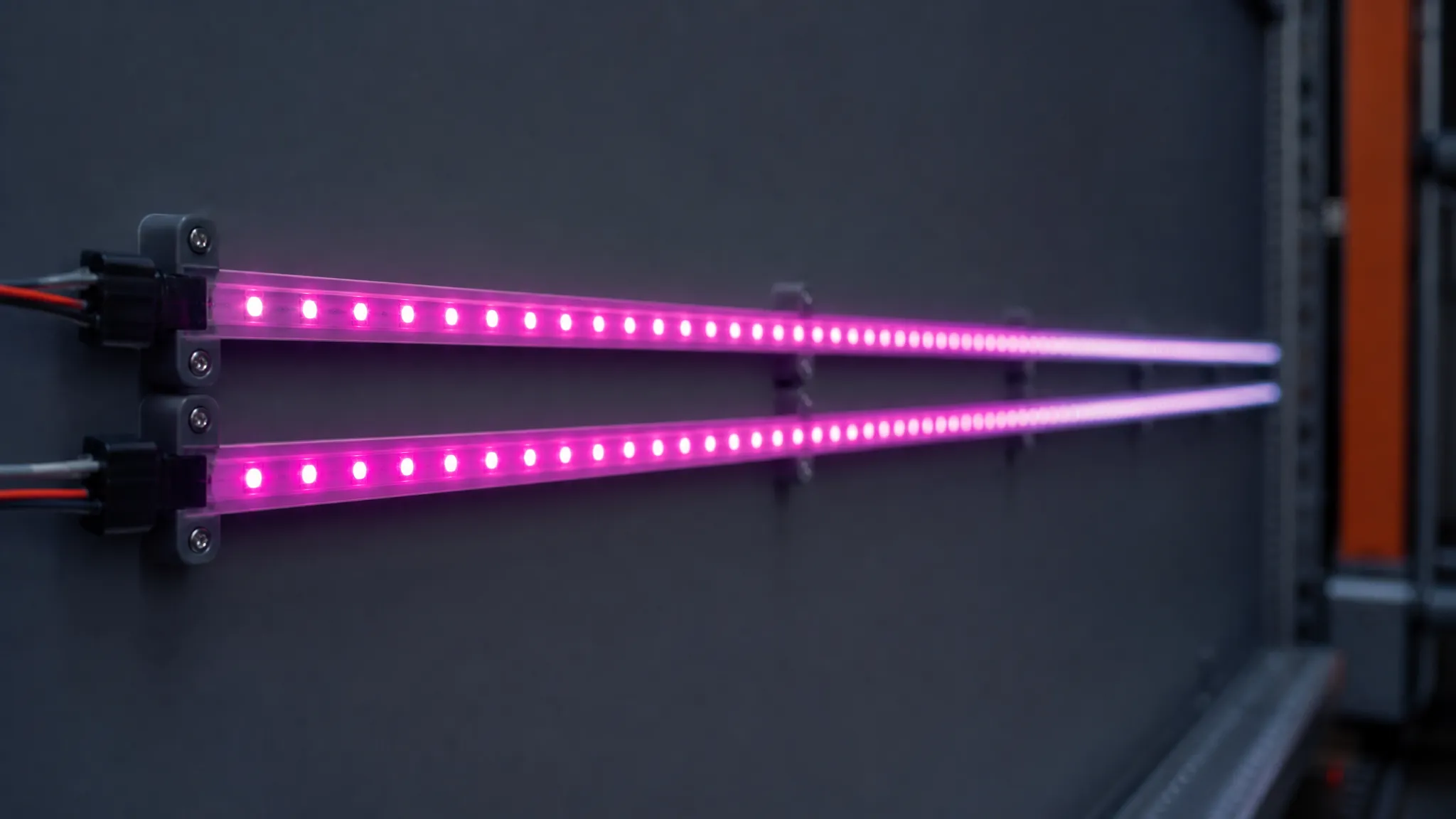 Two addressable LED strip runs mounted on a dark gray wall, both glowing magenta, the upper run lighter towards its right-hand end